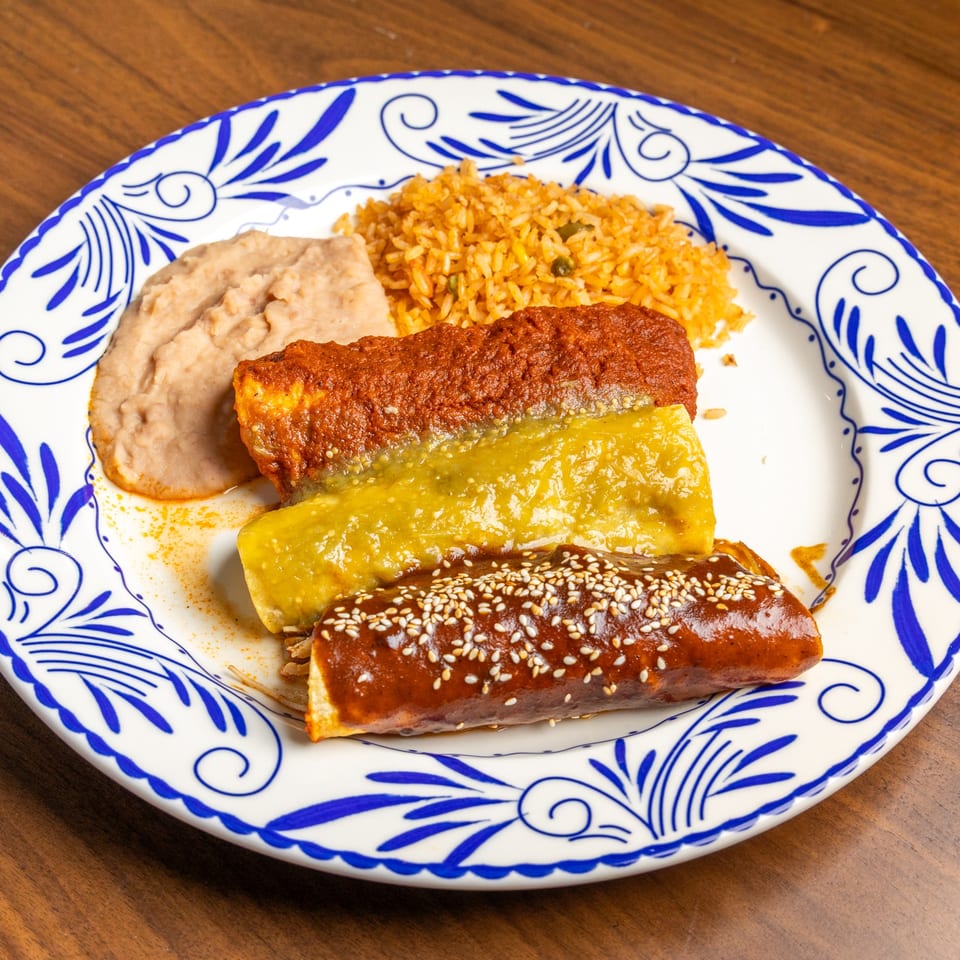 Three enchiladas with red, green, and mole sauces, served with rice and refried beans.