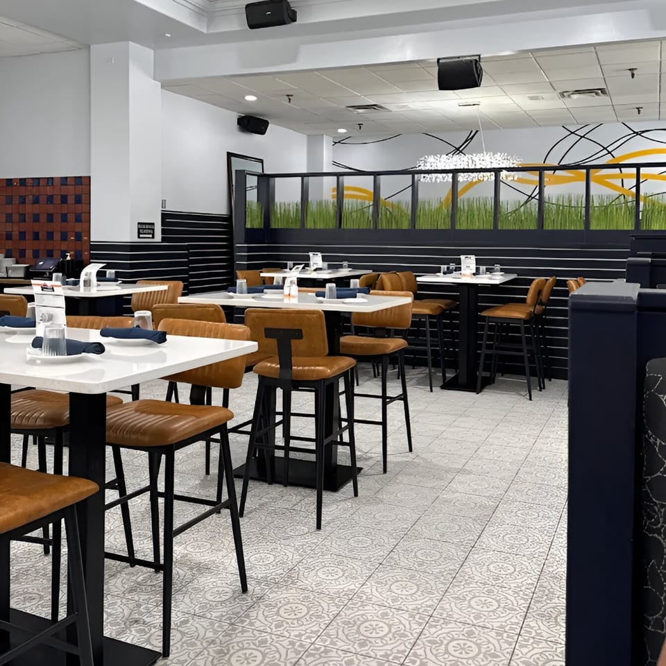 Modern Mexican restaurant interior with high-top tables, brown leather chairs, and patterned floor tiles.
